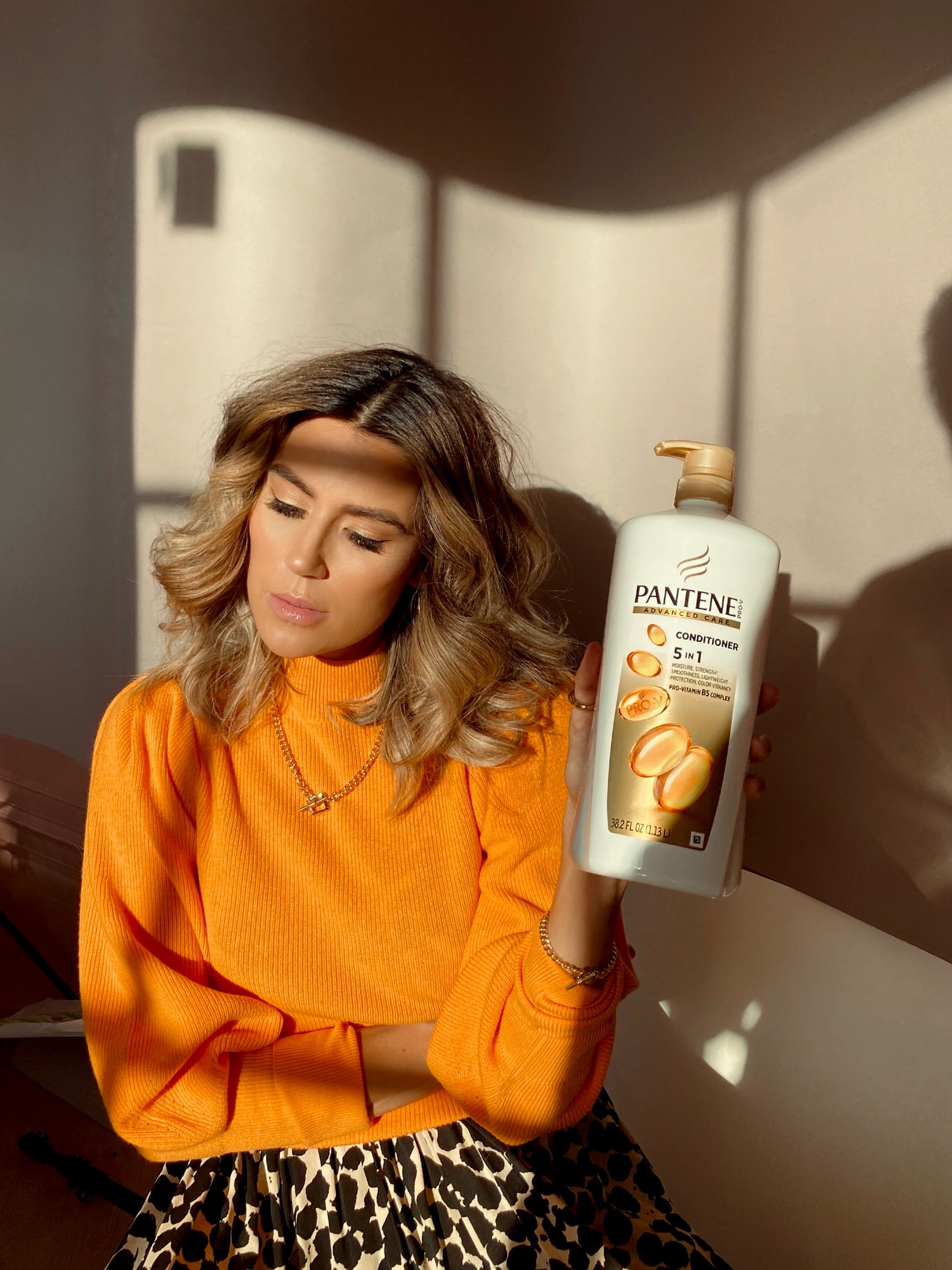 christine andrew in orange sweater holding pantene bottle